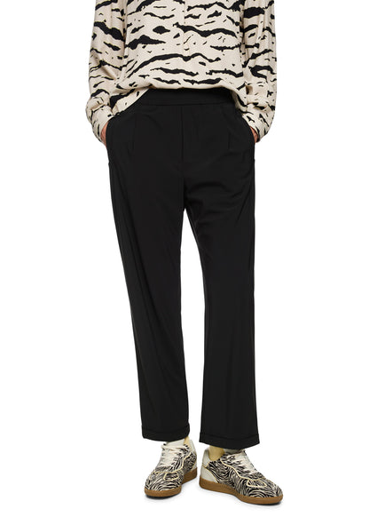 Person wearing a patterned sweater and black pants on a white background