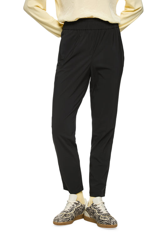 Person wearing black pants and patterned shoes on a white background