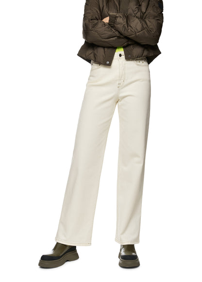 Person wearing a brown jacket and white pants on a white background