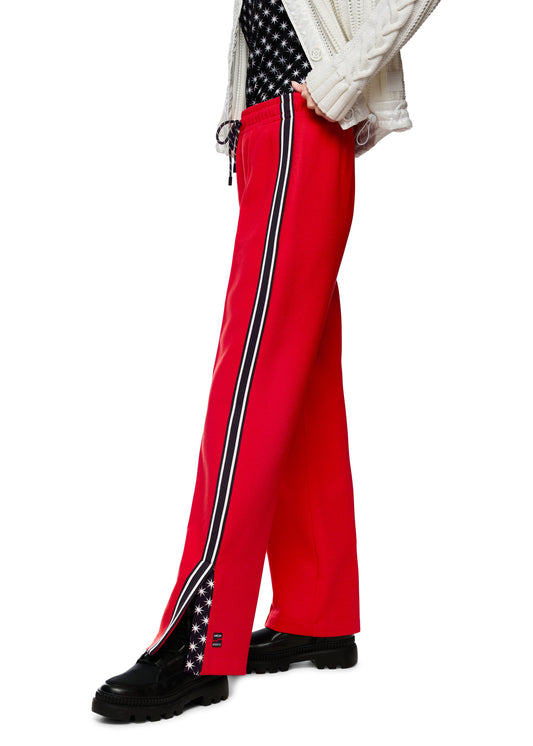 Red pants with a black stripe and American flag design worn by a person on a white background