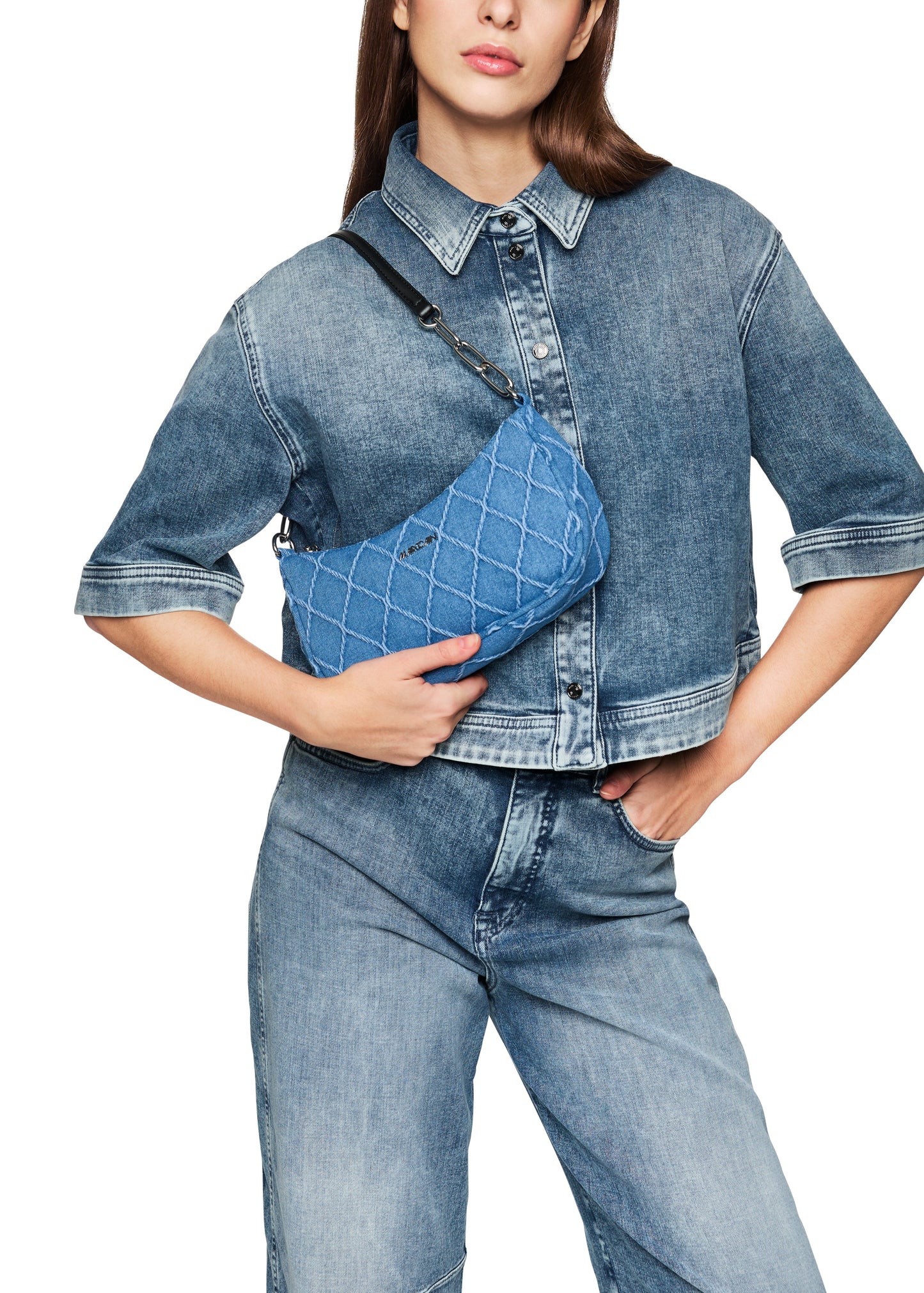 Person wearing a denim outfit with a matching crossbody bag on a white background