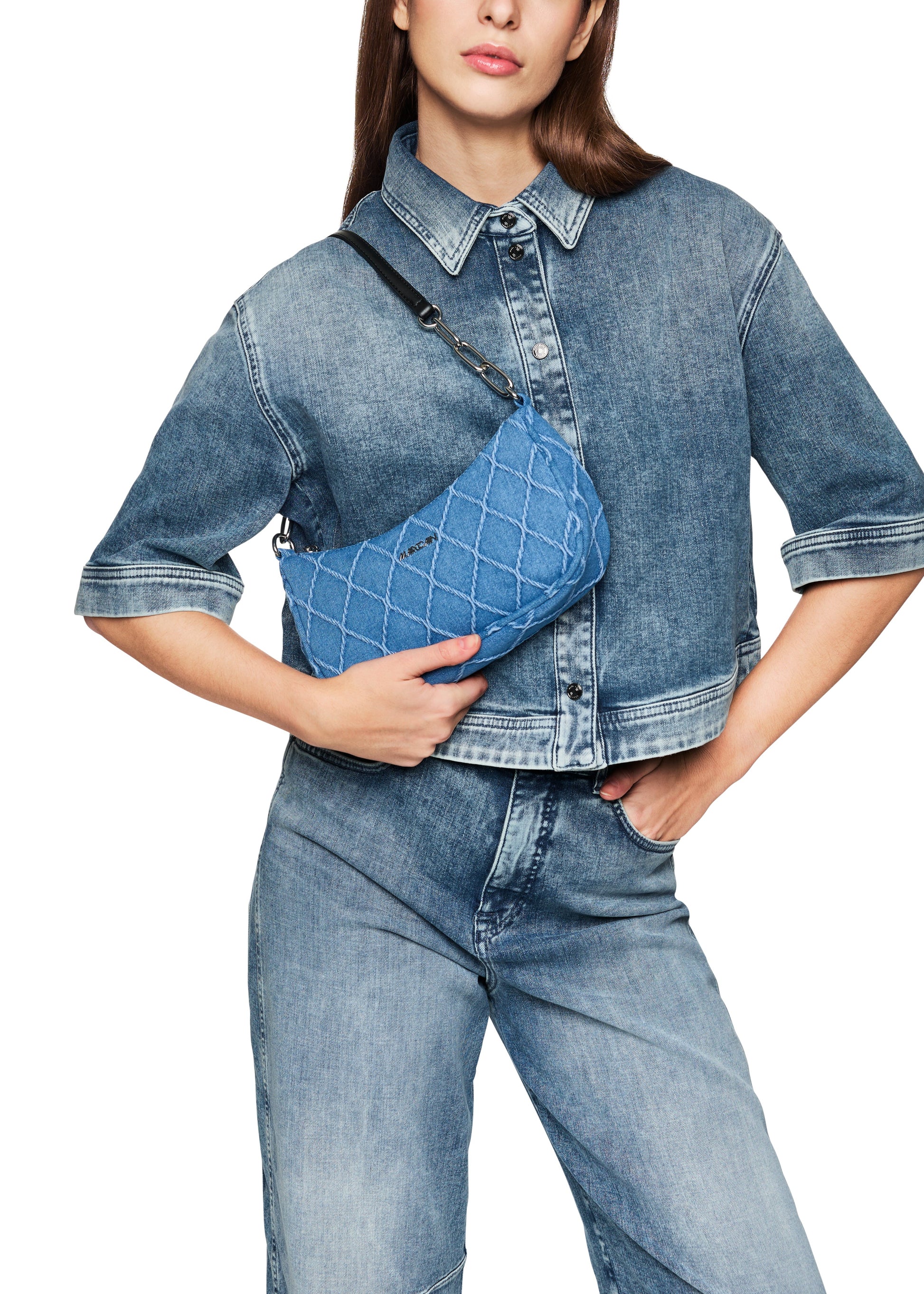 Person wearing a denim outfit with a matching crossbody bag on a white background