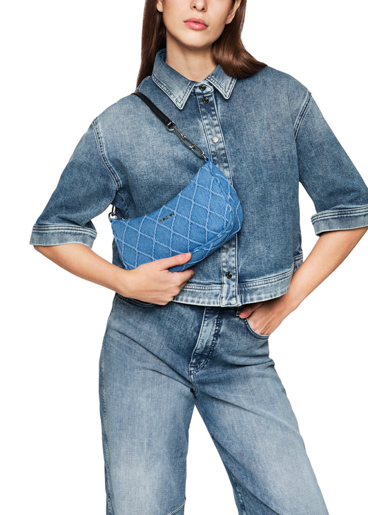 Person wearing a denim outfit with a matching crossbody bag on a white background