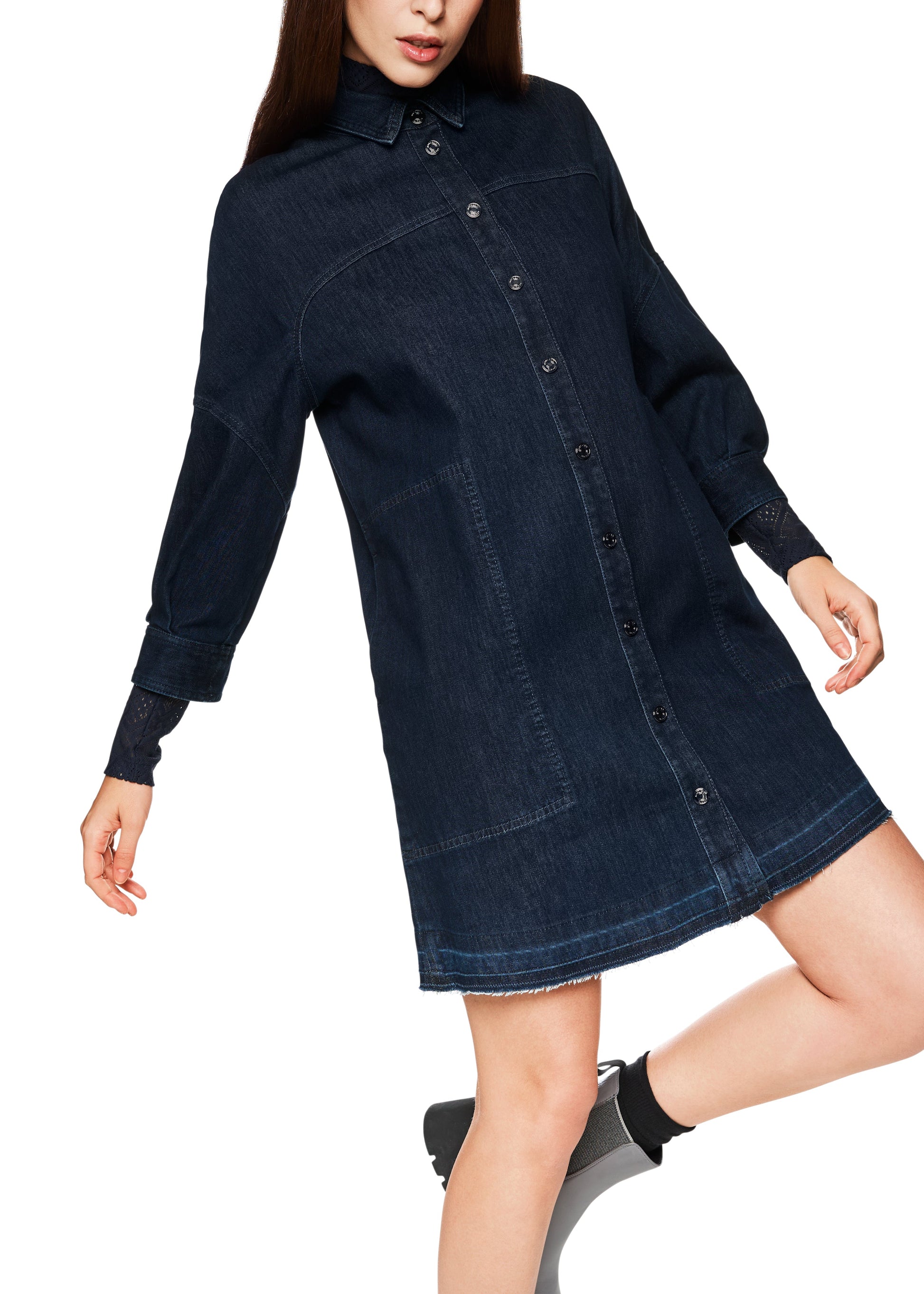 Woman wearing a dark blue denim dress on a white background