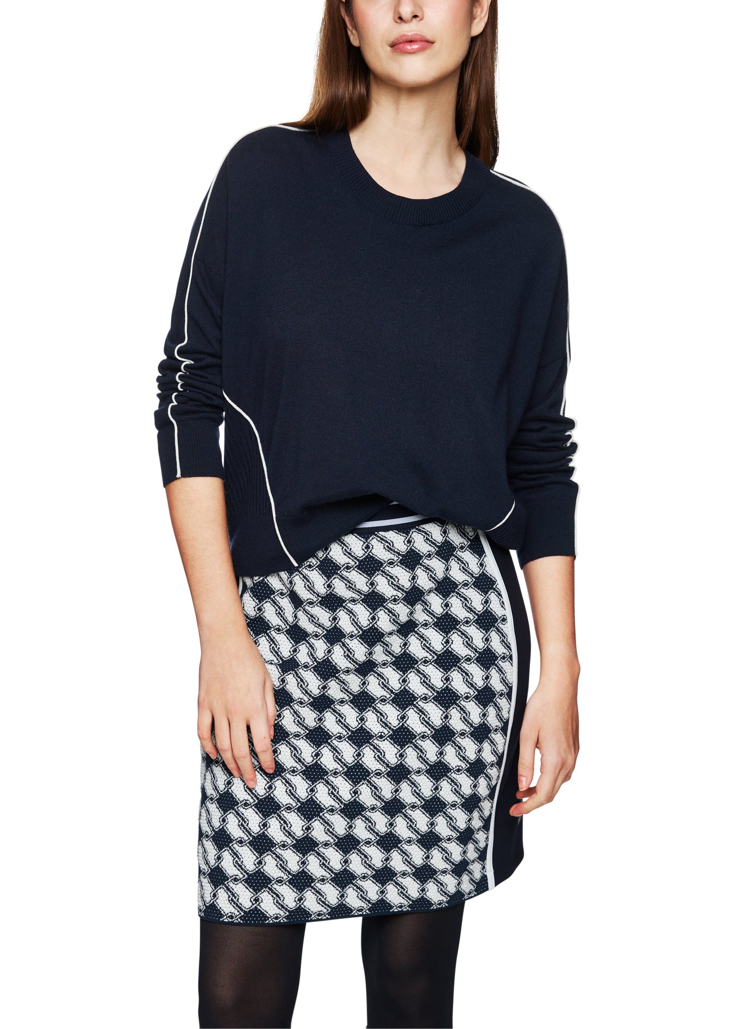 Woman wearing a black sweater with white stripes and a patterned skirt on a white background