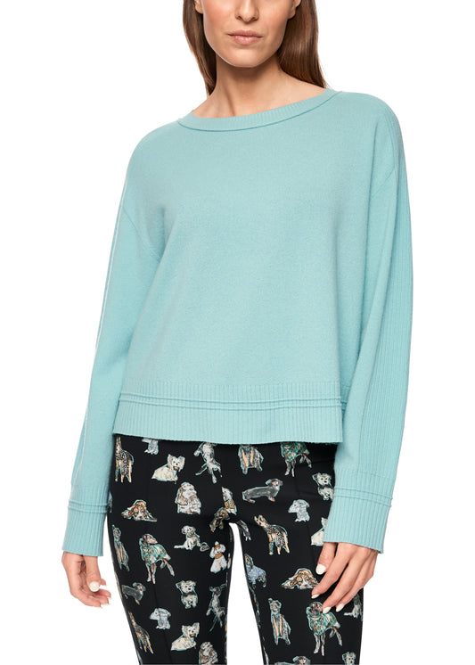 Woman wearing a light blue sweater and patterned pants on a white background