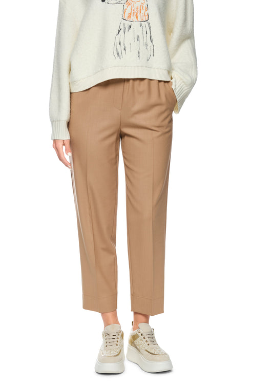 Person wearing beige pants and a white sweater with a graphic design on a white background