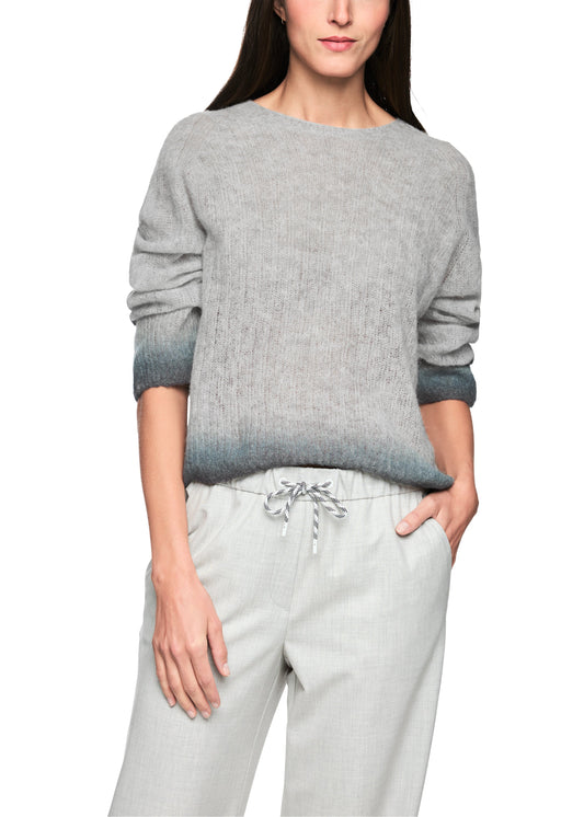 Person wearing a gray sweater and light gray pants on a white background