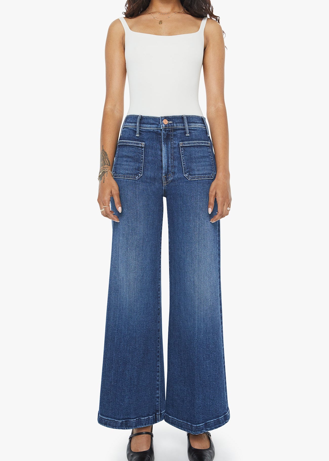 Person wearing blue wide-leg jeans and a white top on a white background