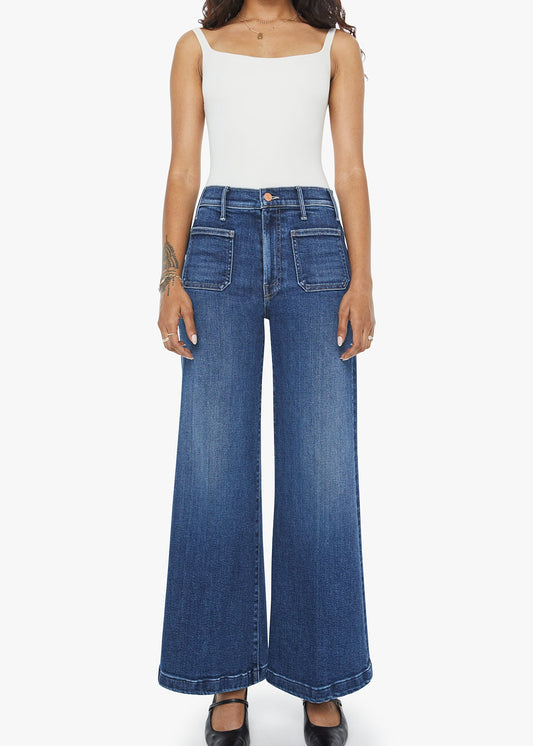 Person wearing blue wide-leg jeans and a white top on a white background