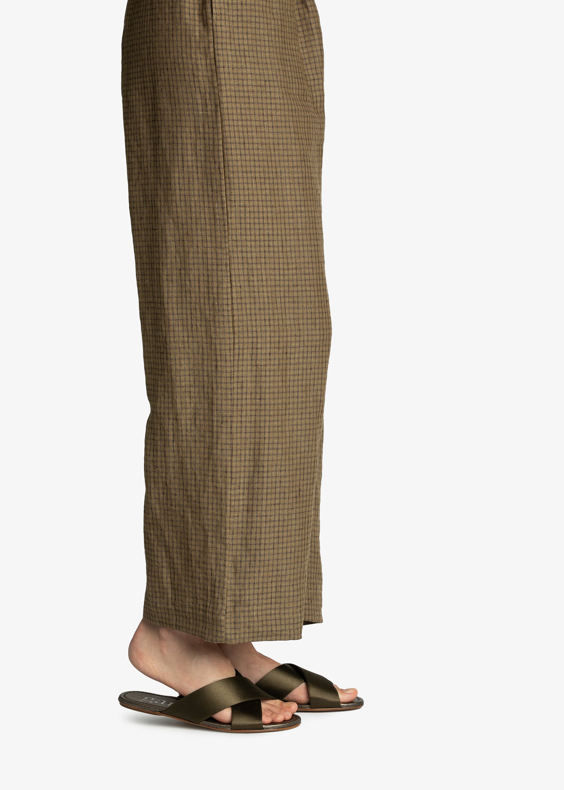 Person wearing brown checkered pants and sandals on a white background