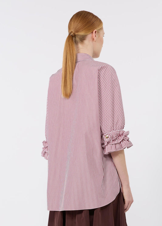 Person wearing a pink and white striped shirt with ruffled sleeves on a white background