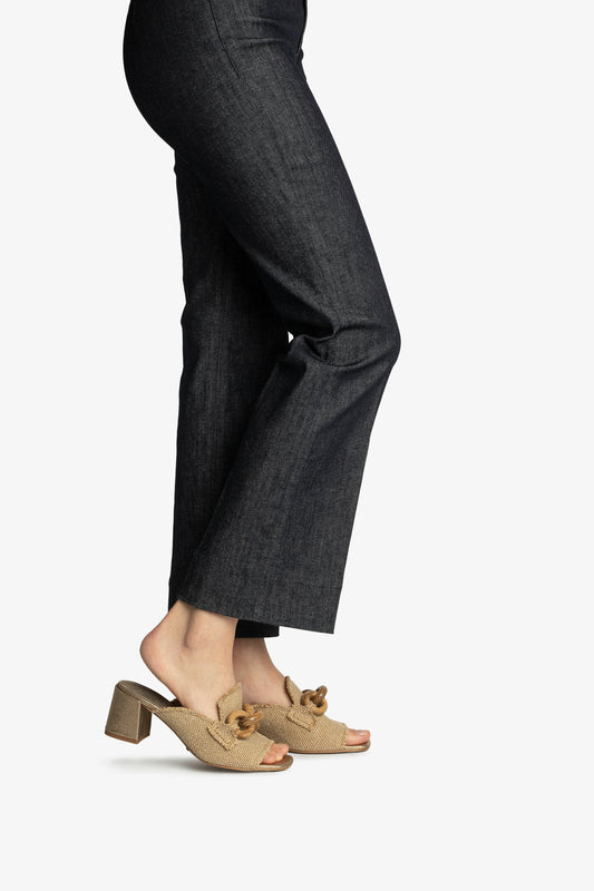 Person wearing dark gray pants and beige sandals on a white background