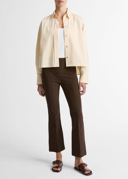 Person wearing a beige shirt, white top, brown pants, and sandals on a white background