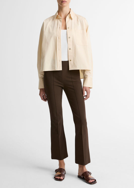 Person wearing a beige shirt, white top, brown pants, and sandals on a white background