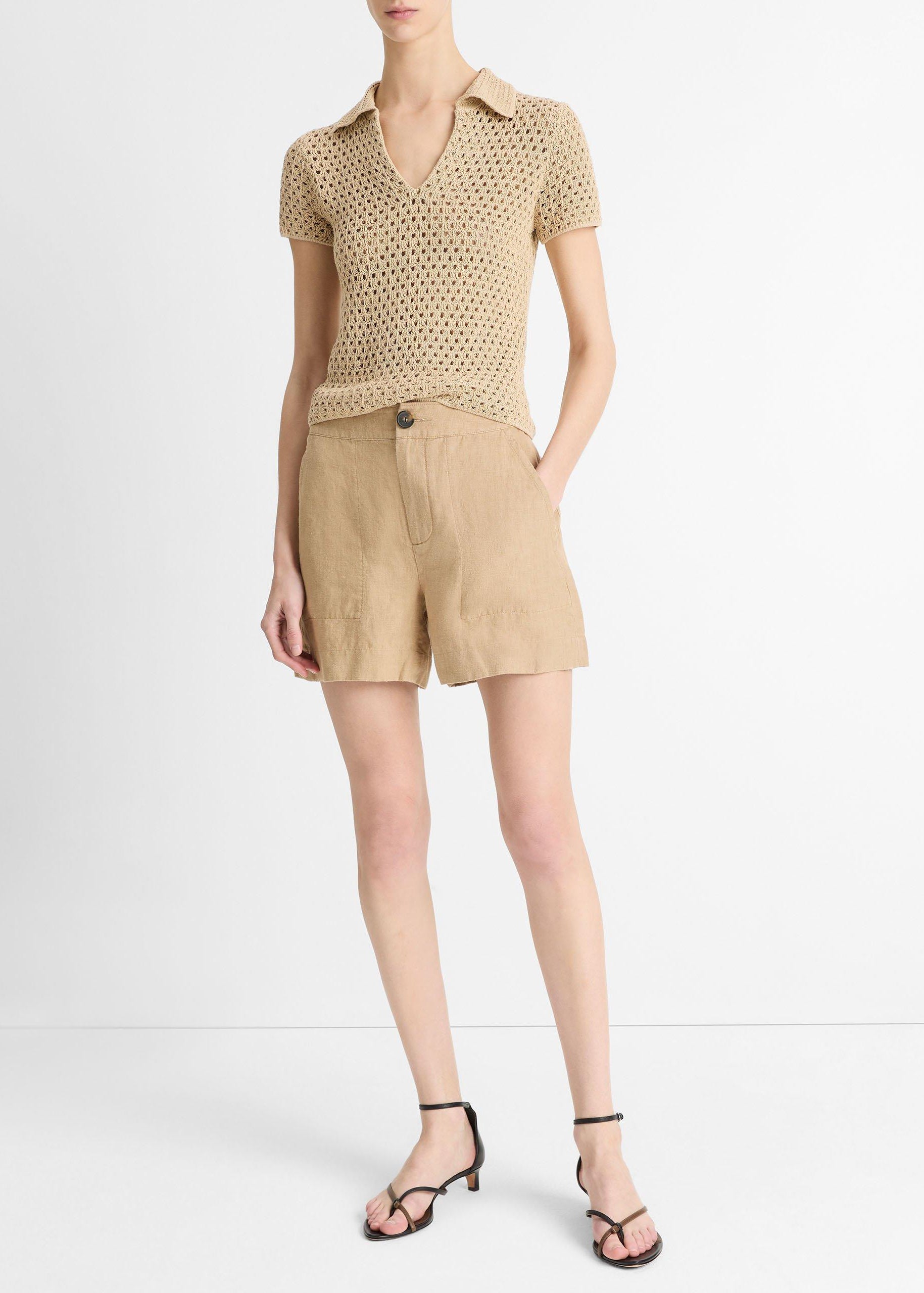 Woman wearing a beige knit top and shorts on a white background