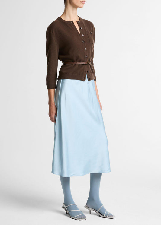 Woman wearing a brown top and light blue skirt on a white background