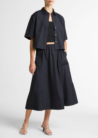 Person wearing a black outfit with a jacket and skirt on a white background