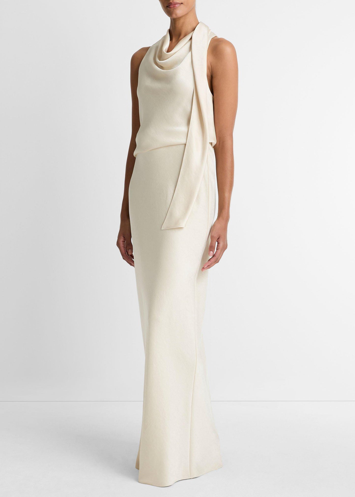 Woman wearing a long, elegant white dress against a plain background