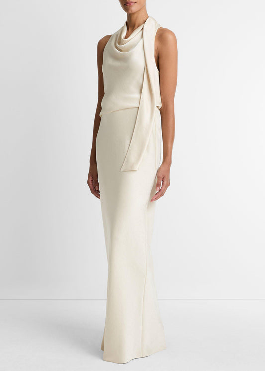 Woman wearing a long, elegant white dress against a plain background