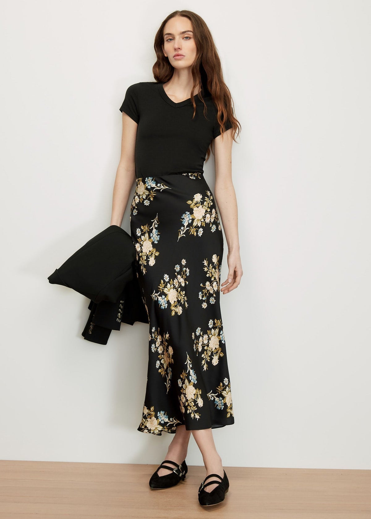 Woman wearing a black top and floral black and white skirt against a white background