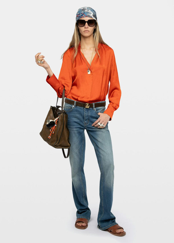 Woman wearing an orange blouse, blue jeans, and a bandana on a white background