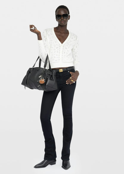 Woman holding a black handbag against a white background
