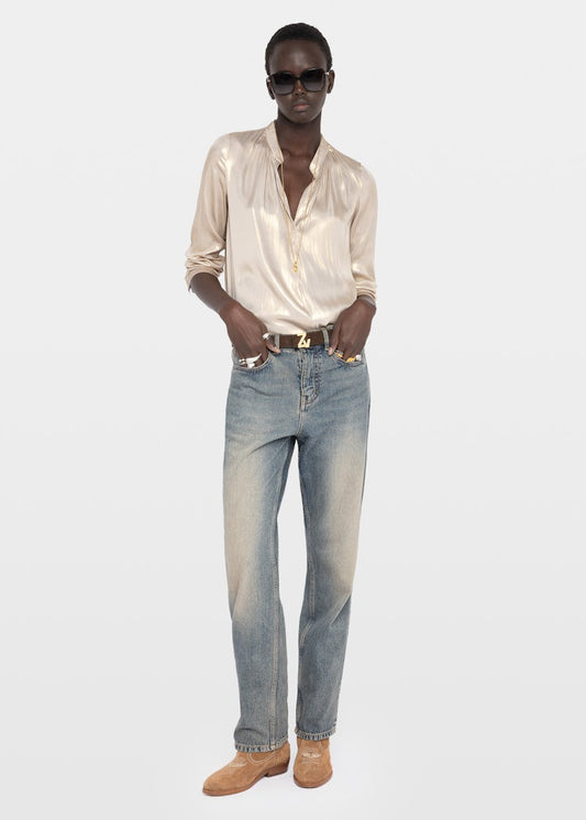 Person wearing a beige shirt and blue jeans on a white background