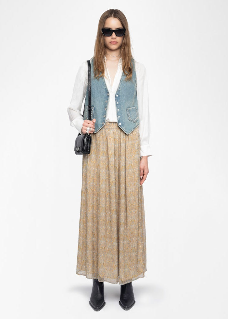 Woman wearing a denim vest, white shirt, beige plaid skirt, and black boots on a white background