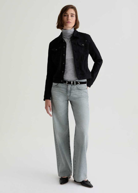 Person wearing a black jacket, gray turtleneck, and light gray jeans on a white background