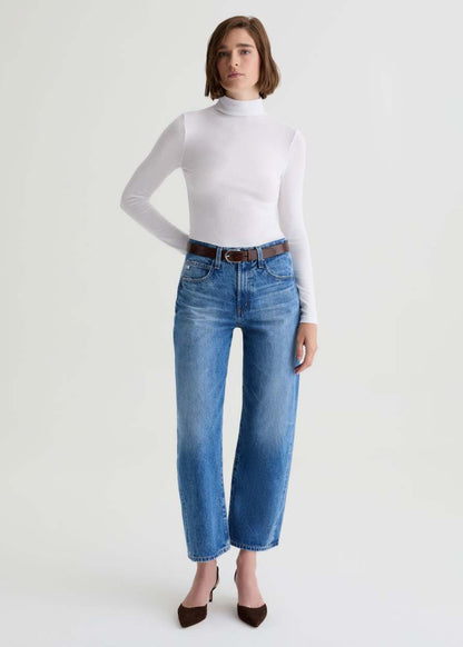 Person wearing a white turtleneck and blue jeans on a white background