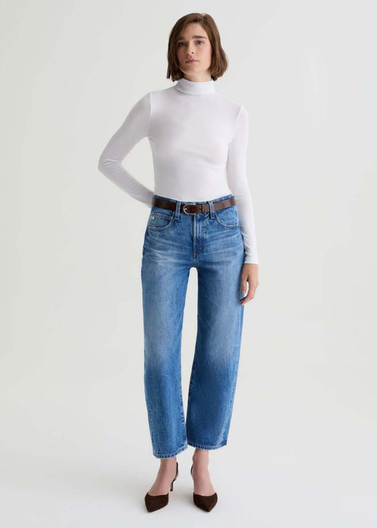 Person wearing a white turtleneck and blue jeans on a white background