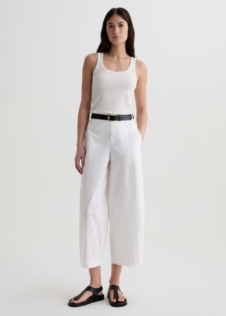 Woman wearing a white sleeveless top and wide-leg pants on a white background