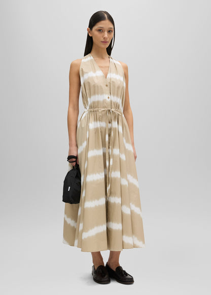 Woman wearing a beige and white striped dress on a gray background