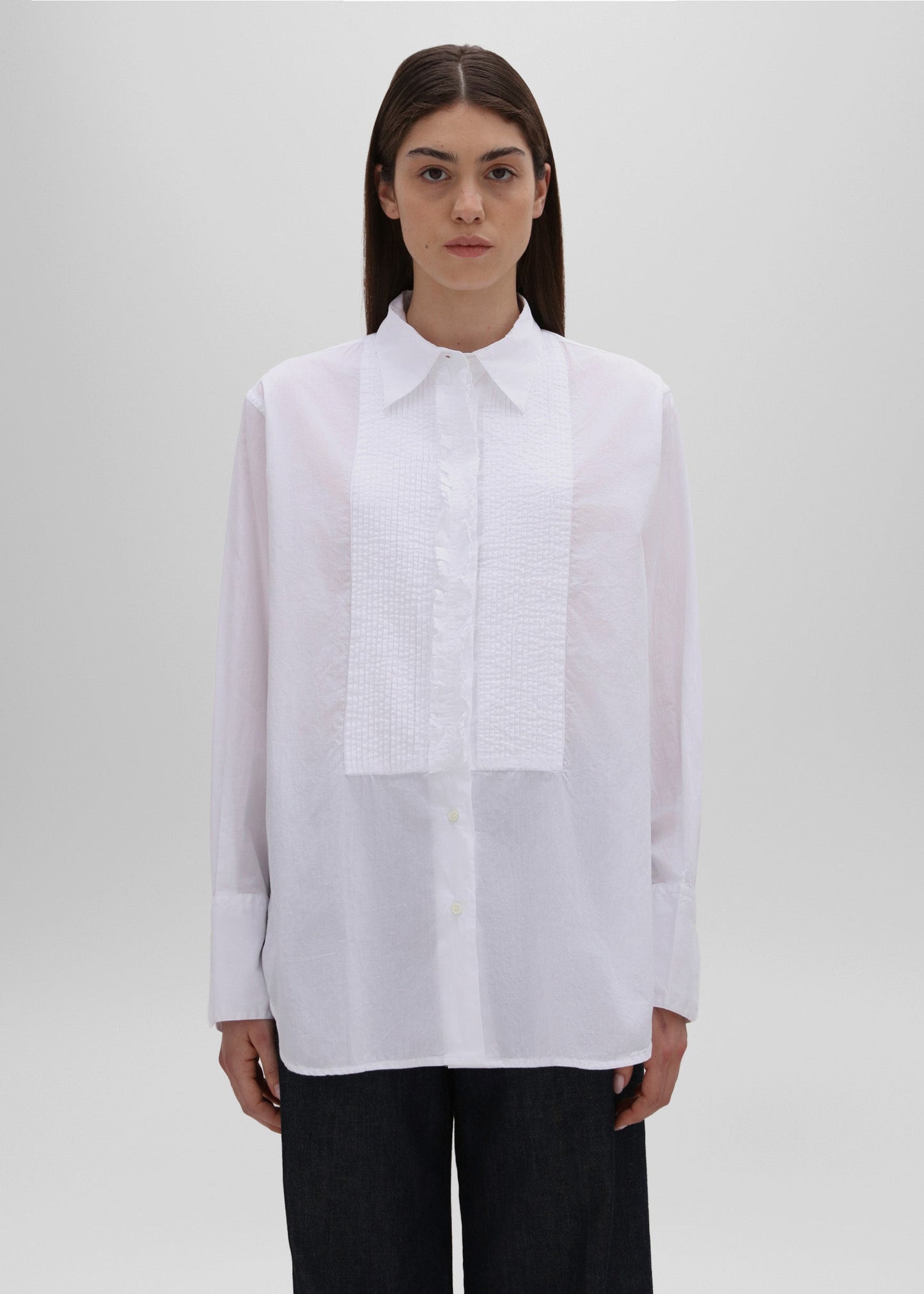 Person wearing a white shirt with a subtle pattern on a plain background