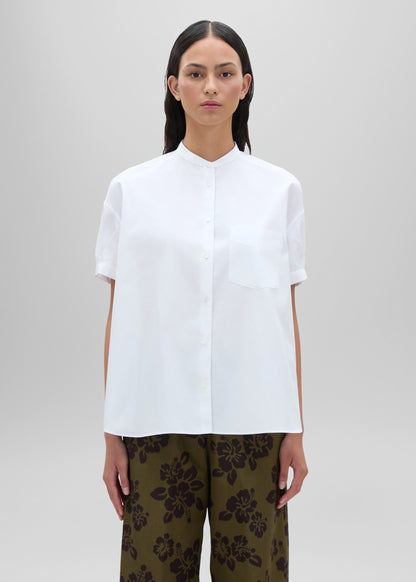 Woman wearing a white shirt and patterned pants on a plain background