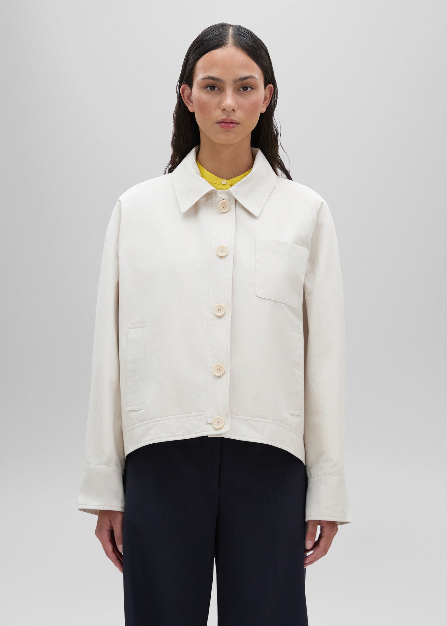 Person wearing a white jacket on a plain background