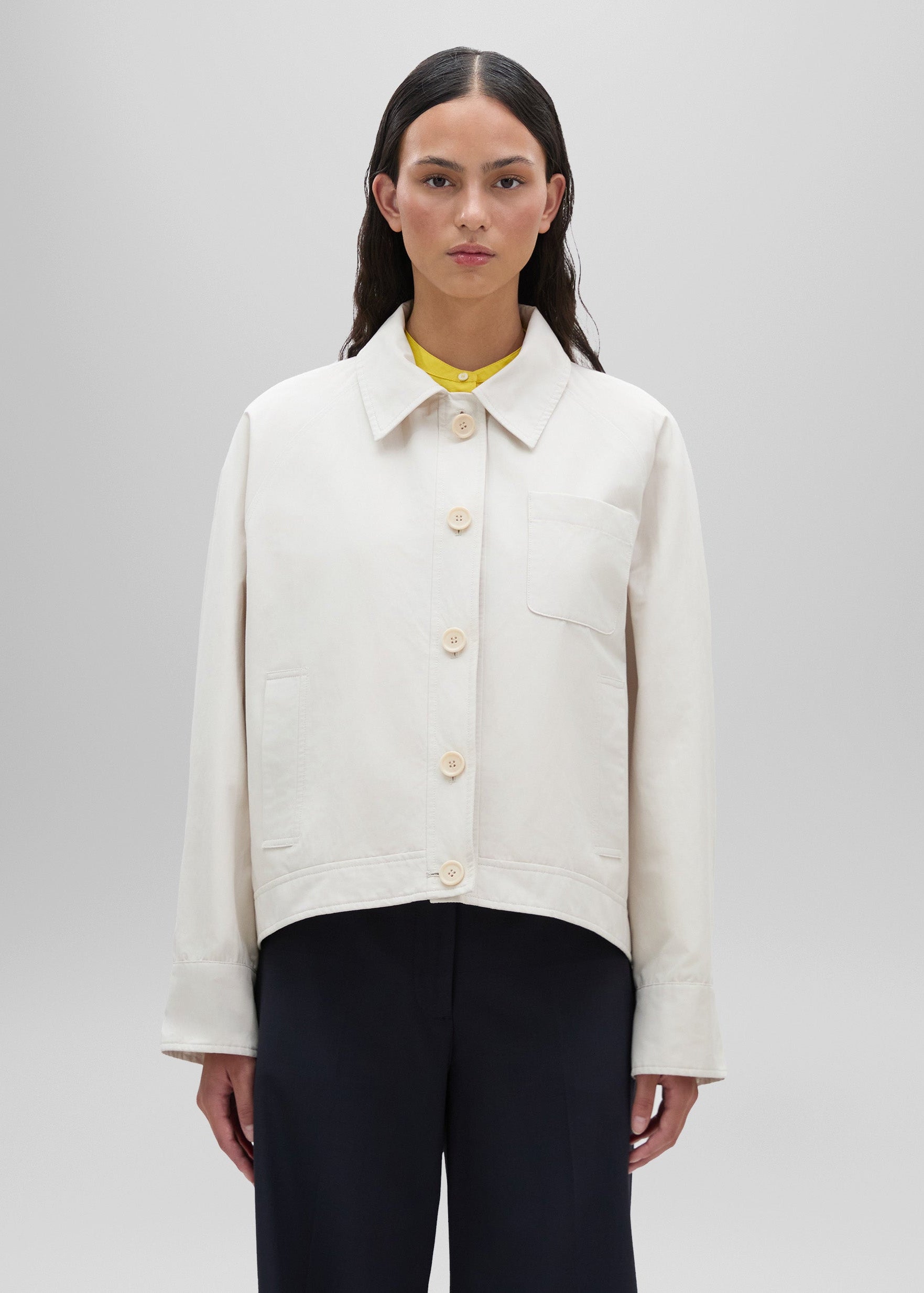 Person wearing a white jacket on a plain background