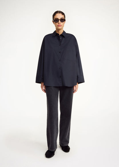 Person wearing a dark navy shirt and gray pants on a white background