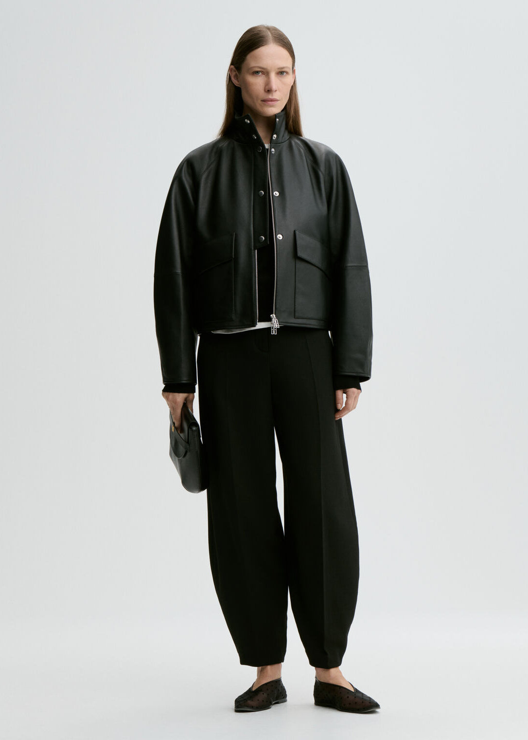 Person wearing a black outfit with a jacket and pants on a white background