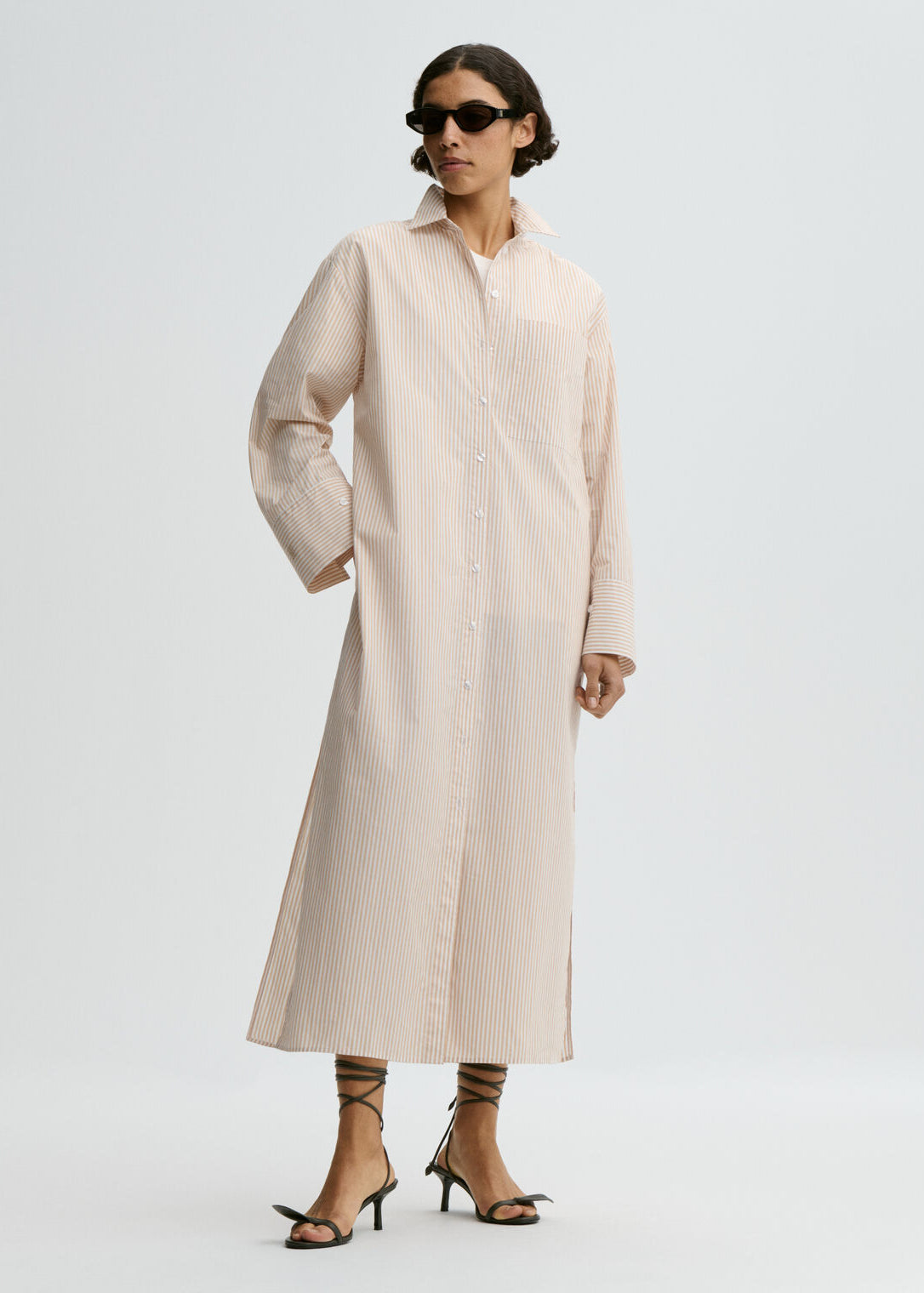 Woman wearing a long beige coat on a white background