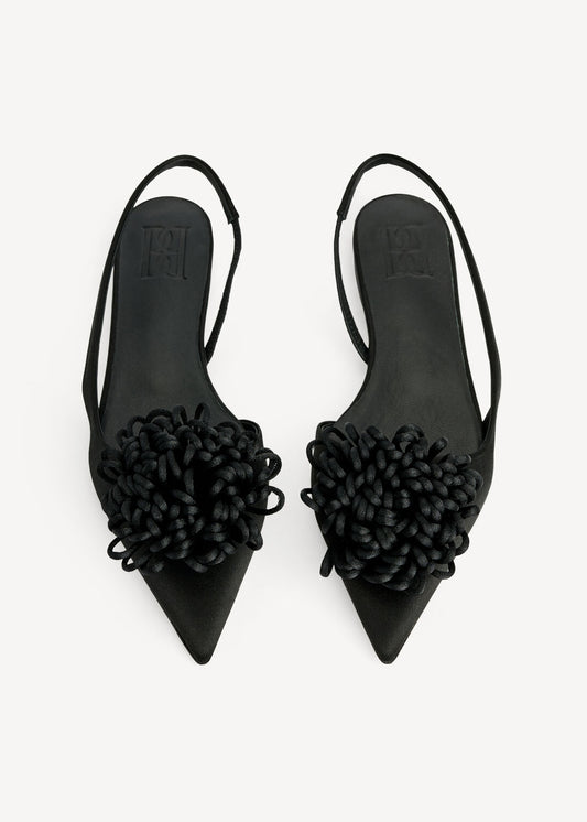 Pair of black pointed-toe shoes with decorative elements on a white background