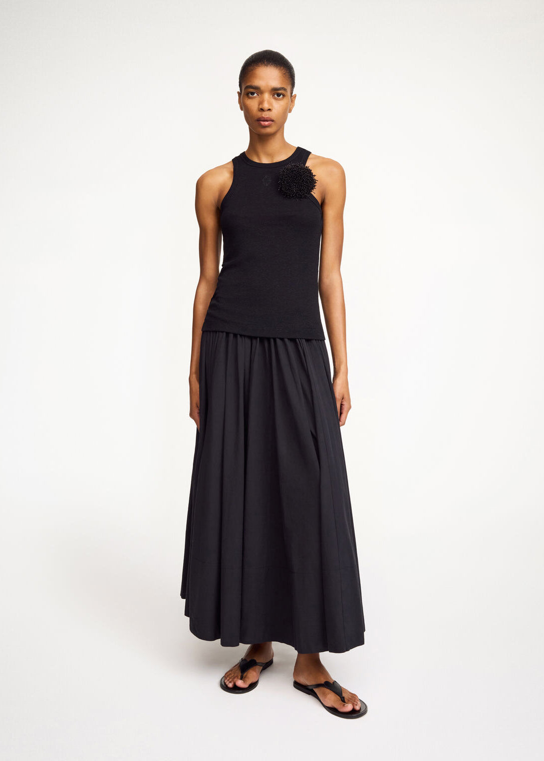 Woman wearing a black sleeveless top and long skirt on a white background
