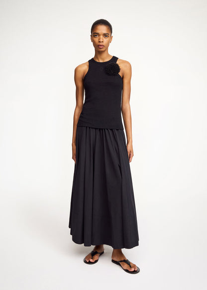 Woman wearing a black sleeveless top and long skirt on a white background