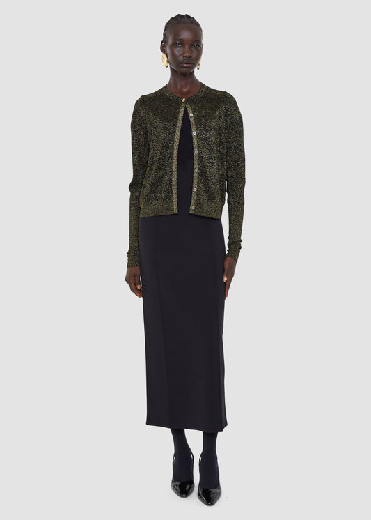 Woman wearing a green sequined cardigan over a black dress on a white background