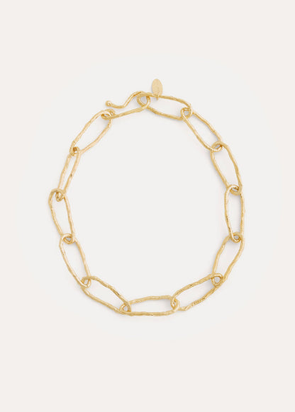 Gold chain bracelet on a light gray background