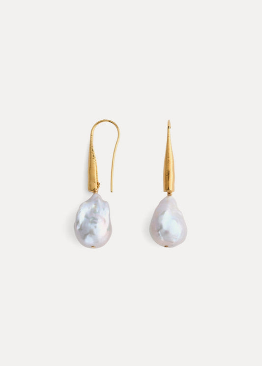 Pair of pearl earrings with gold hooks on a light gray background