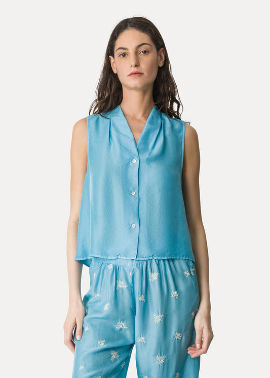 Woman wearing a blue sleeveless top and pants set on a white background