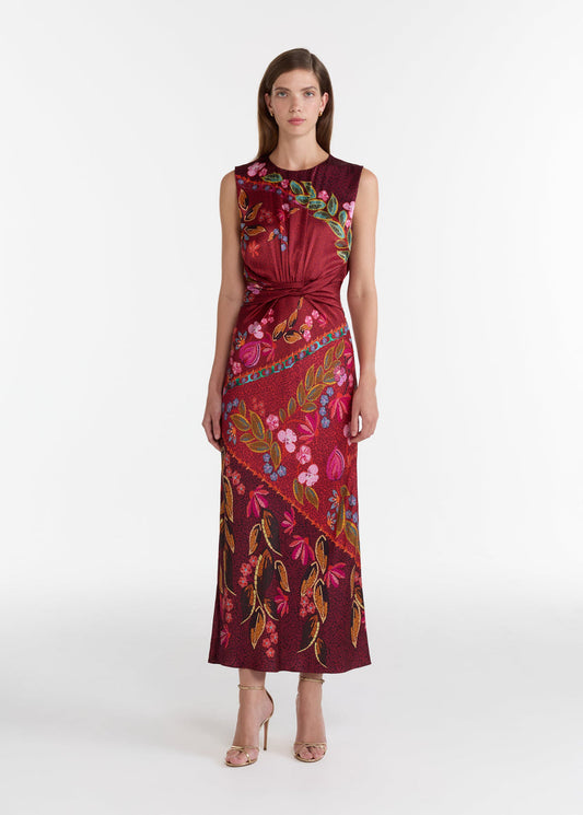 Woman wearing a burgundy dress with floral and leaf patterns on a white background