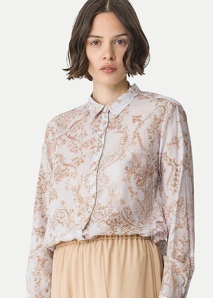 Woman wearing a floral blouse and beige pants on a white background